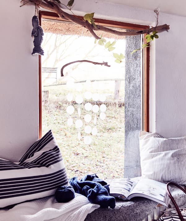 Un siège près de la fenêtre avec des coussins rayés et des plaids.