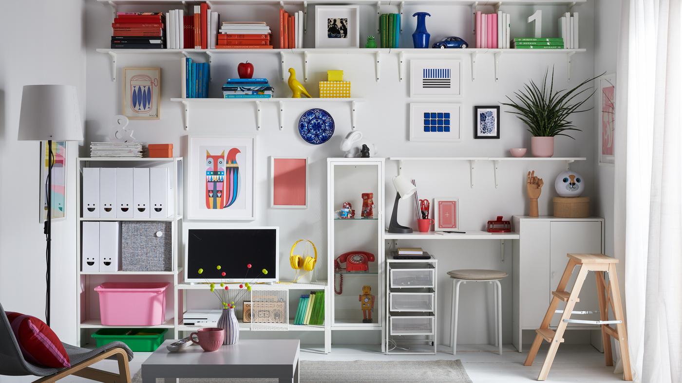 Un soggiorno con una parete intera di mensole e mobili per organizzare libri, giocattoli, oggetti da collezione e riviste - IKEA