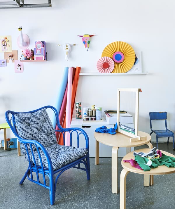 Un telaio per tessitura e dei ritagli di tessuto su un set di due tavolini, una sedia con braccioli e una parete dedicata alle creazioni artistiche - IKEA