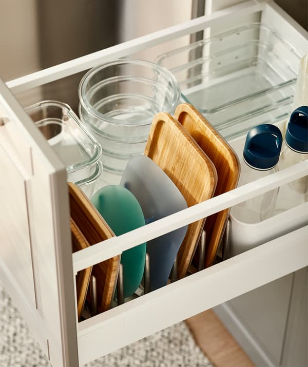 Un tiroir de cuisine rempli de piles de boîtes repas en verre de différents formats, avec leur couvercles respectifs en file dans un range-couvercles.