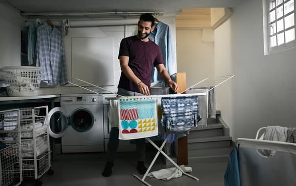 Un uomo stende il bucato in un locale lavanderia - IKEA