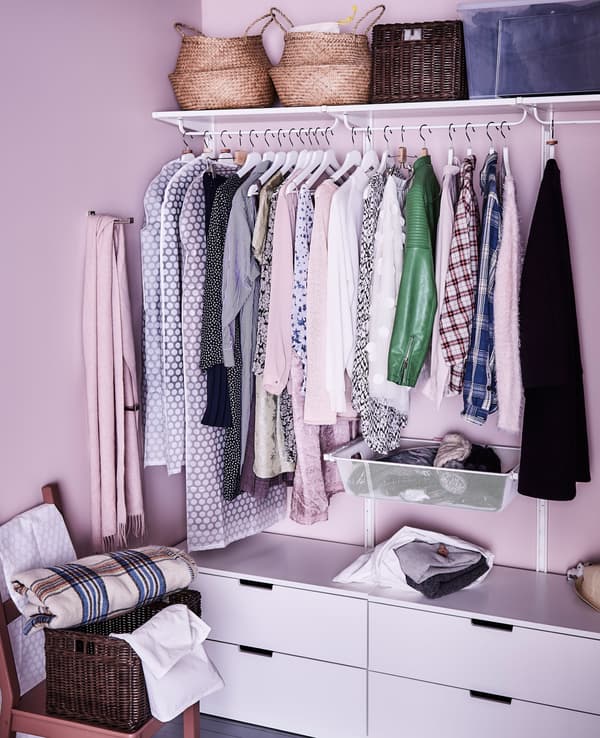 Una cabina armadio organizzata con cassetti, grucce e contenitori sul ripiano in alto - IKEA.