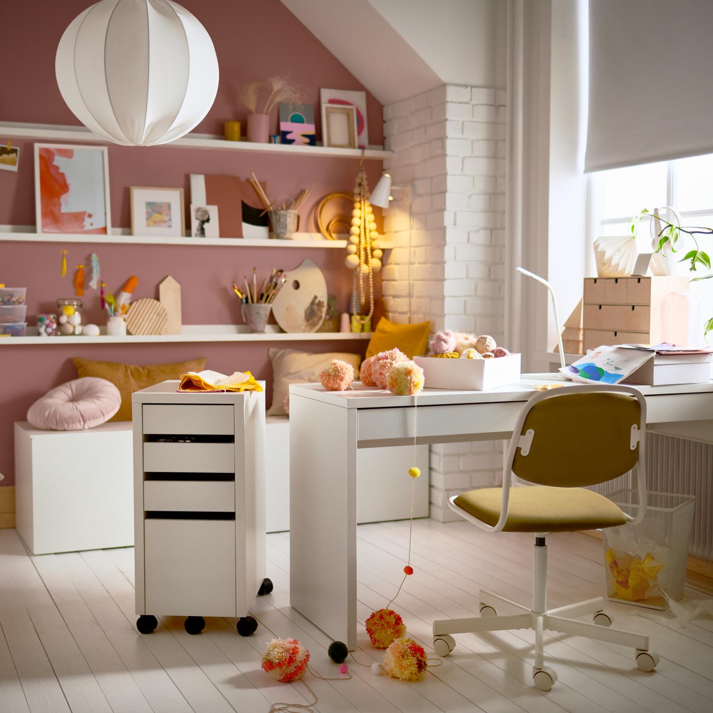 Una cameretta con una scrivania MICKE bianca, una sedia da scrivania per bambini, una cassettiera bianca e mensole per quadri con decorazioni.