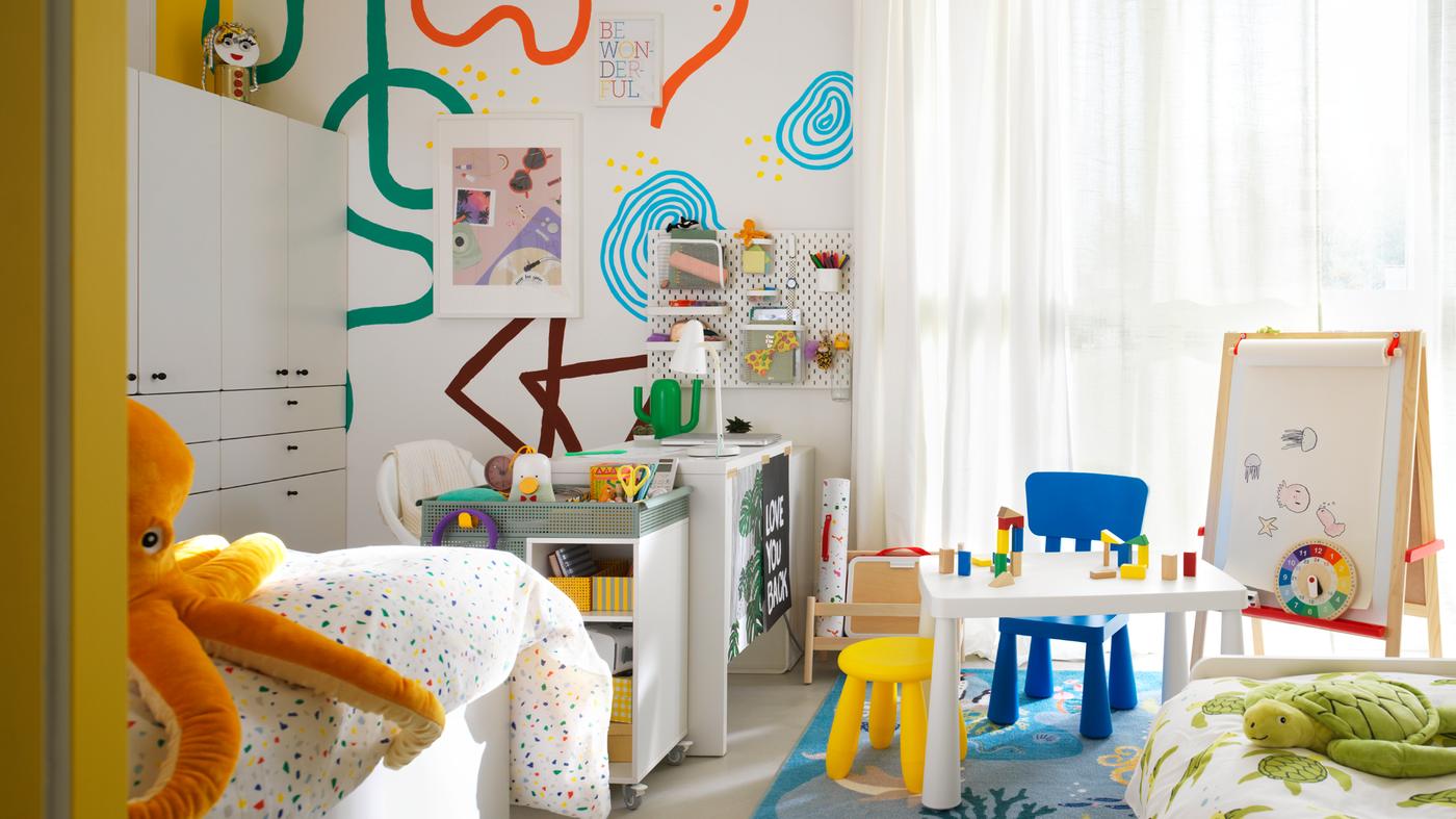 Una cameretta condivisa con mobili per bambini MAMMUT accanto a una scrivania MICKE bianca e un carrello ÖVNING - IKEA.
