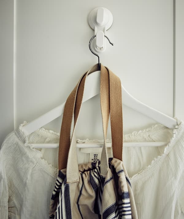 Una camicia bianca e una borsa su una gruccia appesa a un gancio bianco - IKEA