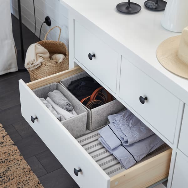 Una cassettiera HEMNES aperta, con scatole KOMPLEMENT grigio chiaro, utili per organizzare i capi di abbigliamento - IKEA