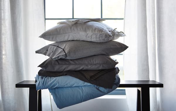 Una catasta di cuscini e biancheria da letto in diversi materiali, che aiutano a regolare la temperatura mentre si dorme - IKEA