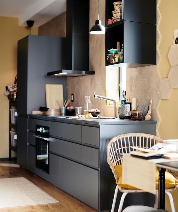 Una cucina lineare nera con una cappa da parete in una stanza giallo tenue - IKEA