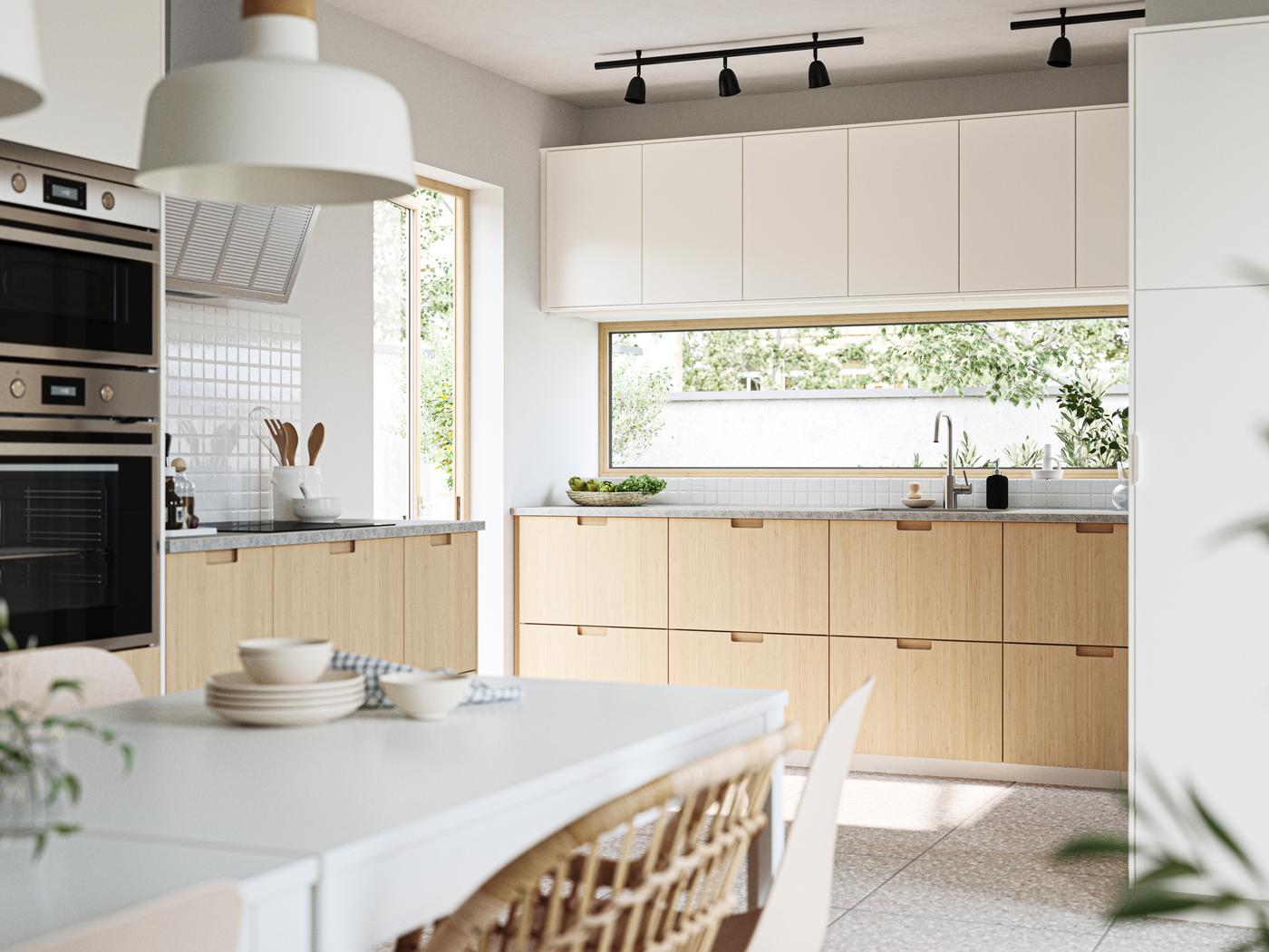 Una cucina moderna inondata dal sole. I mobili in basso hanno frontali FRÖJERED e gli elementi top hanno frontali VEDDINGE.