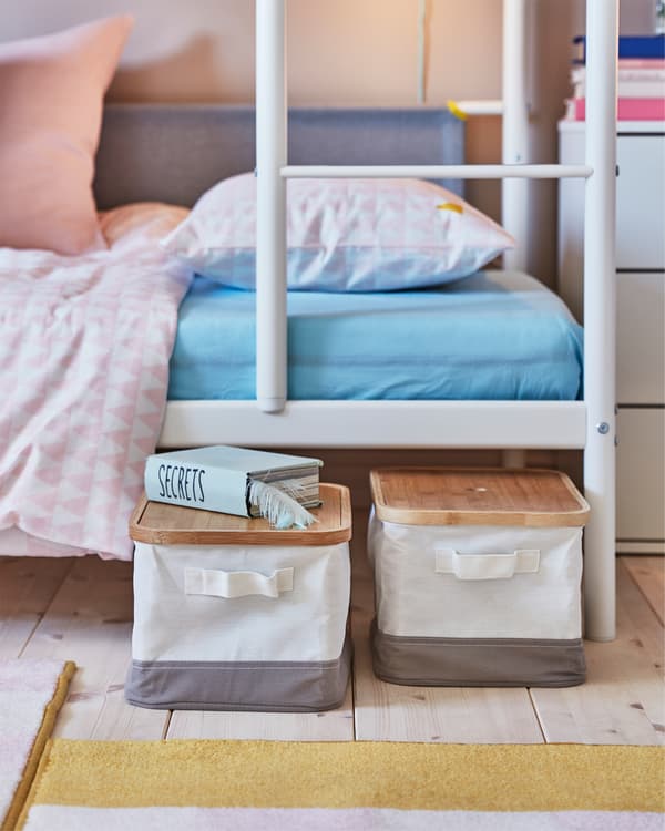 Una habitación infantil donde las cajas RABBLA con tapas de bambú son extraídas debajo de una litera blanca.