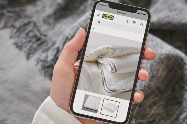 Una mano con un celular navegando en el sitio IKEA online.