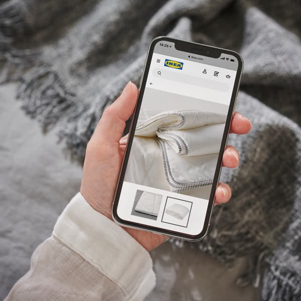 Una mano con un celular navegando en el sitio IKEA online.