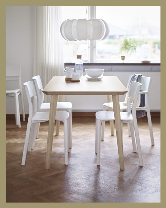 Una mesa de comedor LISABO con 4 sillas plásticas blancas.