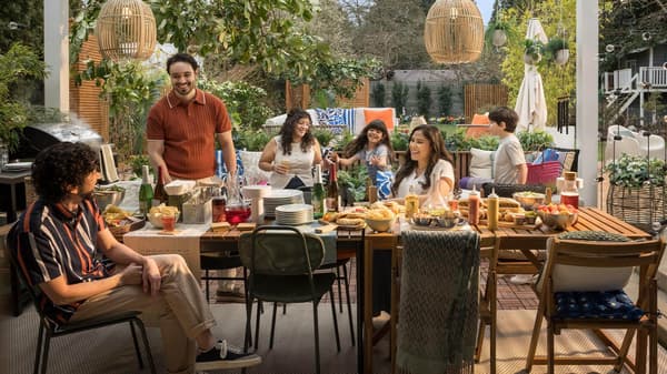 Una mesa de comedor para exteriores colorida con una familia reunida a su alrededor.