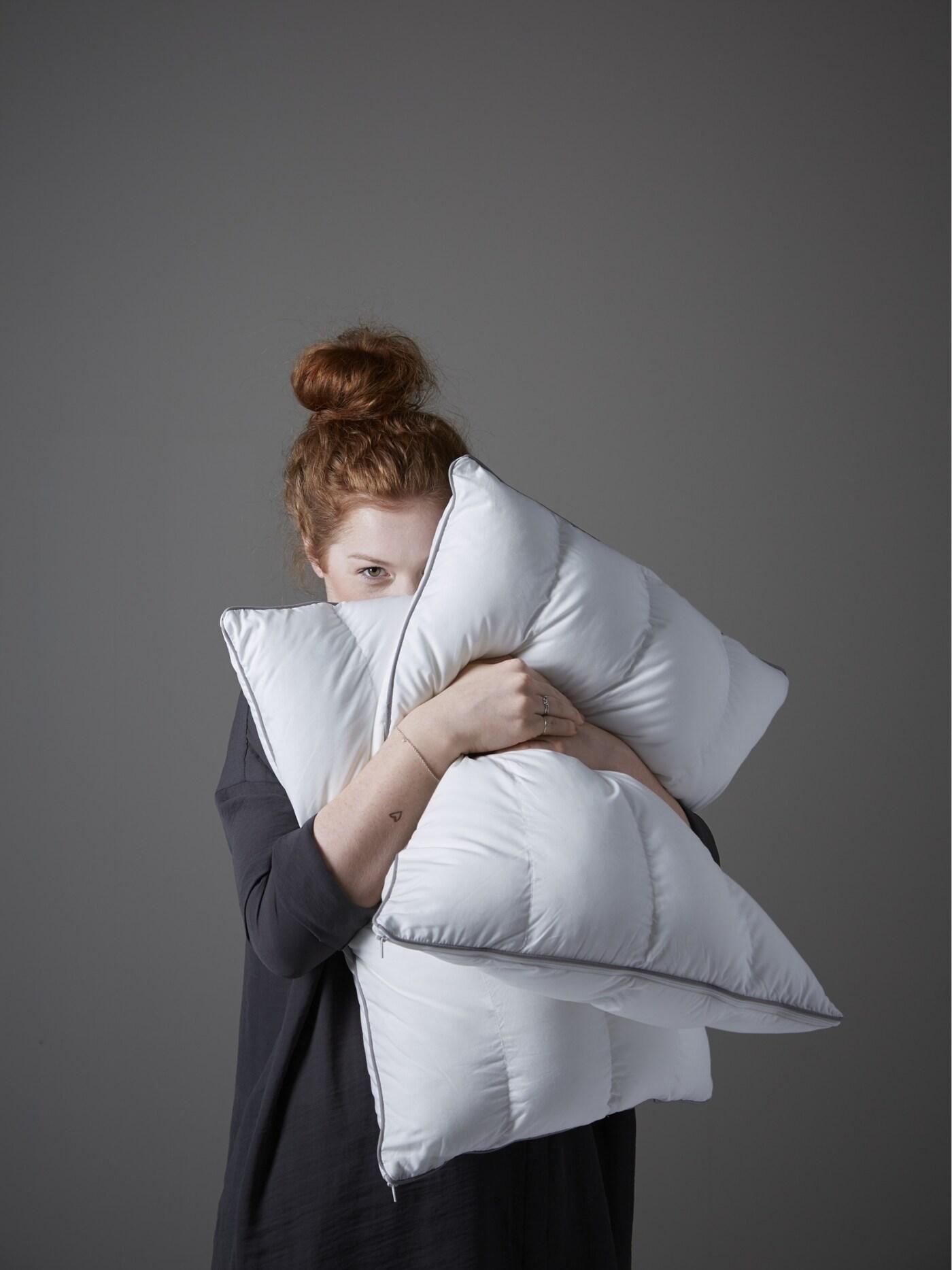 Una mujer colorina abrazando dos almohadas IKEA.