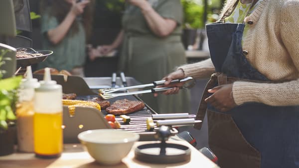 Una persona alrededor de una parrilla volteando un trozo de carne con un accesorio GRILLTIDER.