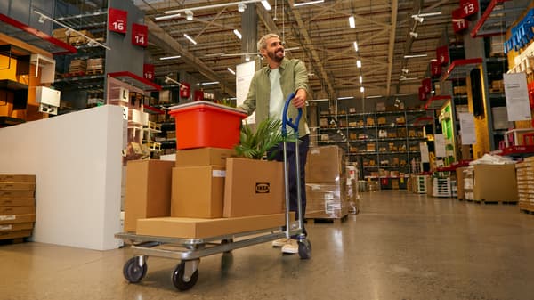 Una persona saliendo de IKEA con un carro con cajas planas.