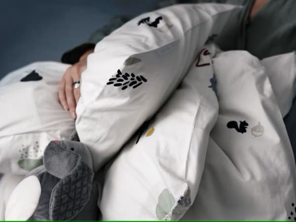 Una persona sujetando almohadas y edredones blancos IKEA.