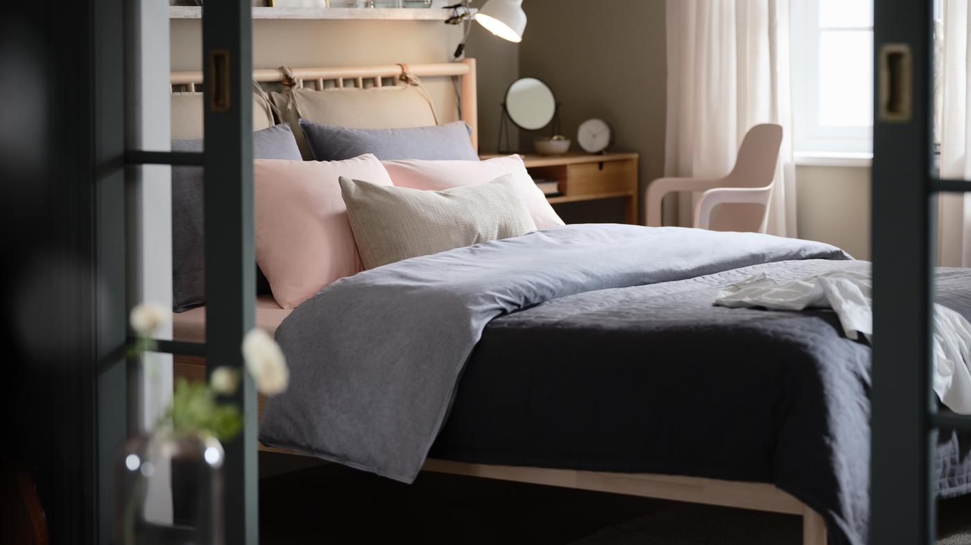 Una recámara con cama BJÖRKSNÄS, ropa de cama KOPPARBLAD azul oscuro, tocador NORDKISA y silla giratoria ODGER.