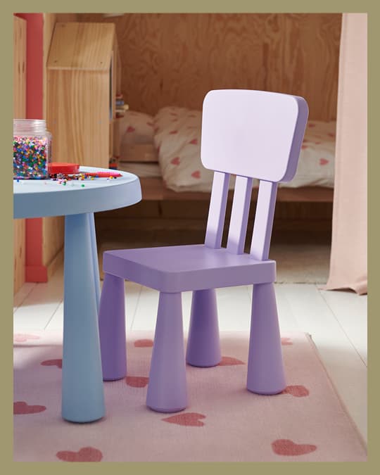 Una silla infantil MAMMUT morada sobre una alfombra infantil.