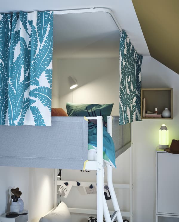 Una struttura per letto a soppalco circondata da tende bianche/turchesi appese a binari fissati al soffitto, per garantire la dovuta privacy - IKEA
