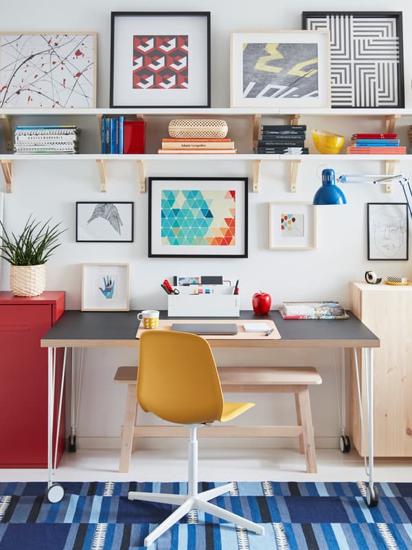 Une chaise pivotante LEIFARNE et un bureau à roulettes LINNMON/KRILLE forment un espace de travail entouré de rangement et d’œuvres d’art.