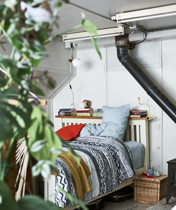 Une chambre à coucher avec du linge de lit à motif et des livres posés sur une tête de lit.