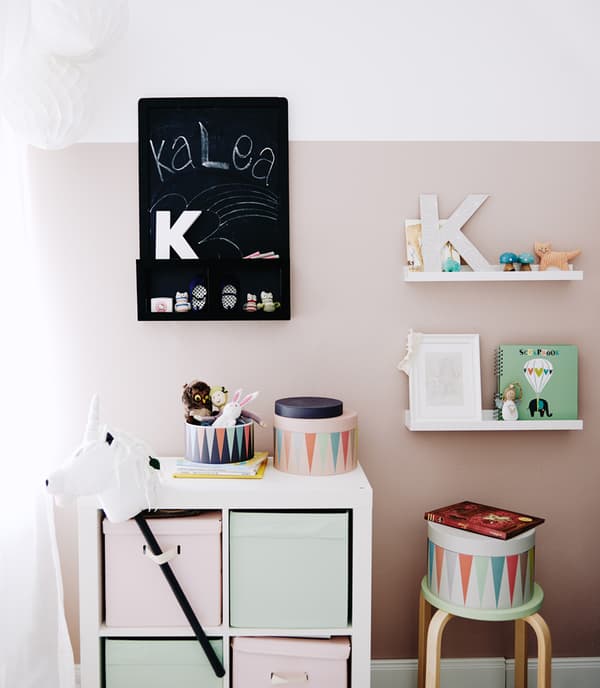 Une chambre d’enfant avec des rangements dans des couleurs pastel.