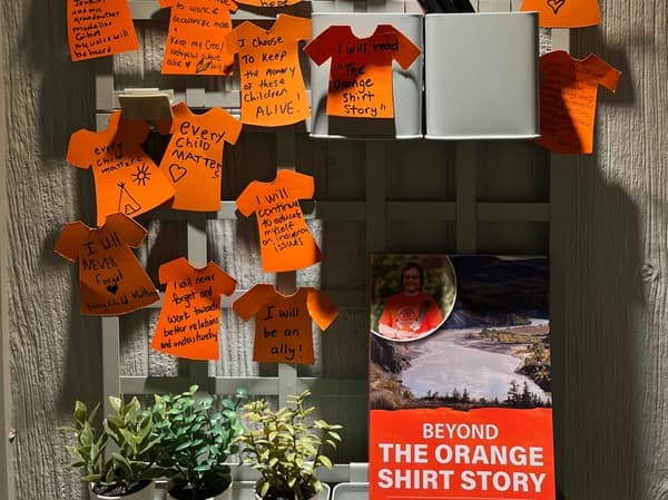 Une collection de papiers orange est collée sur un tableau accroché au mur. 