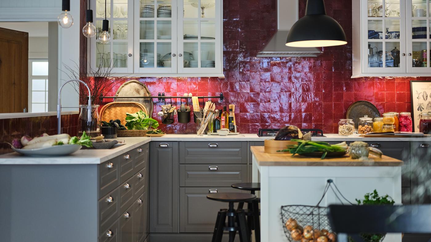 Une cuisine au carrelage rouge avec des rangements muraux blancs, des rangements METOD avec des aménagements intérieurs MAXIMERA, un îlot blanc avec un plan de travail en bois.