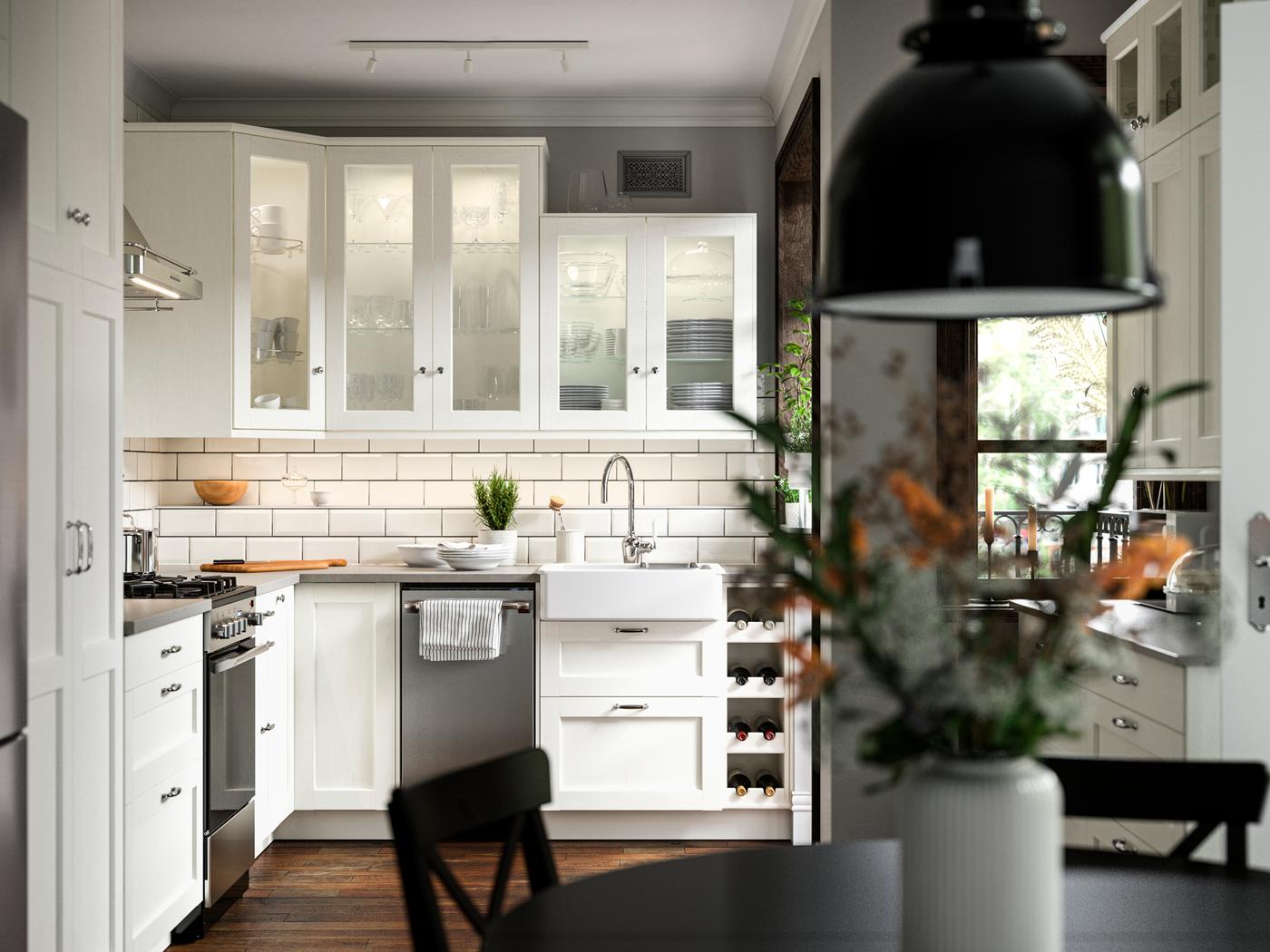 Une cuisine avec des façades ENKÖPING blanches, une cuisinière CIRKULERA en acier inoxydable, un évier HAVSEN et une suspension SVARTNORA.