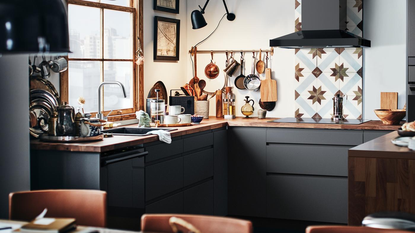 Une cuisine moderne SEKTION avec des façades d"armoires gris foncé, un comptoir en bois et un dosseret de comptoir en céramique.