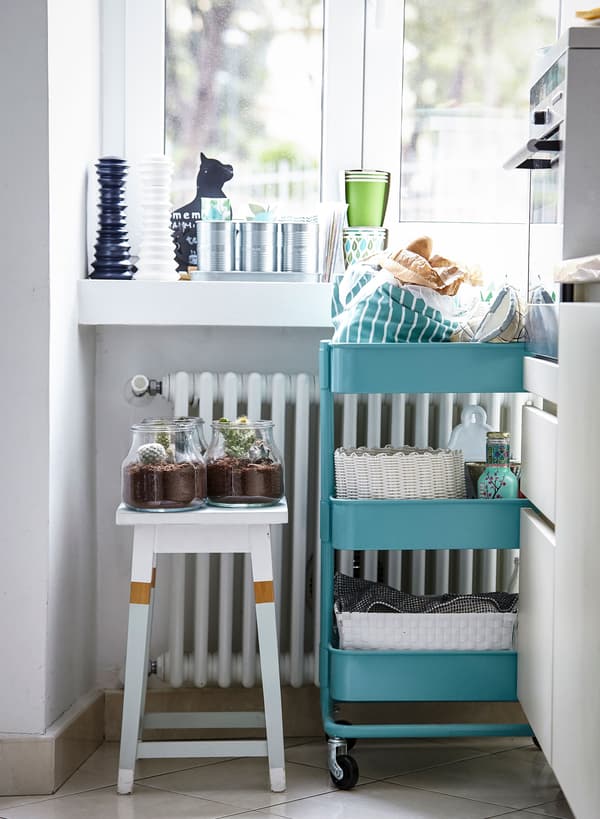 Une desserte RÅSKOG et un tabouret blanc offrent un rangement flexible et mobile dans cette cuisine lumineuse mais minuscule.