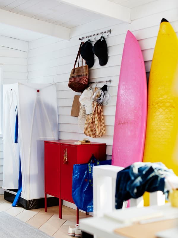 Une entrée au style décontracté avec une armoire-penderie VUKU et une commode LIXHULT rouge.