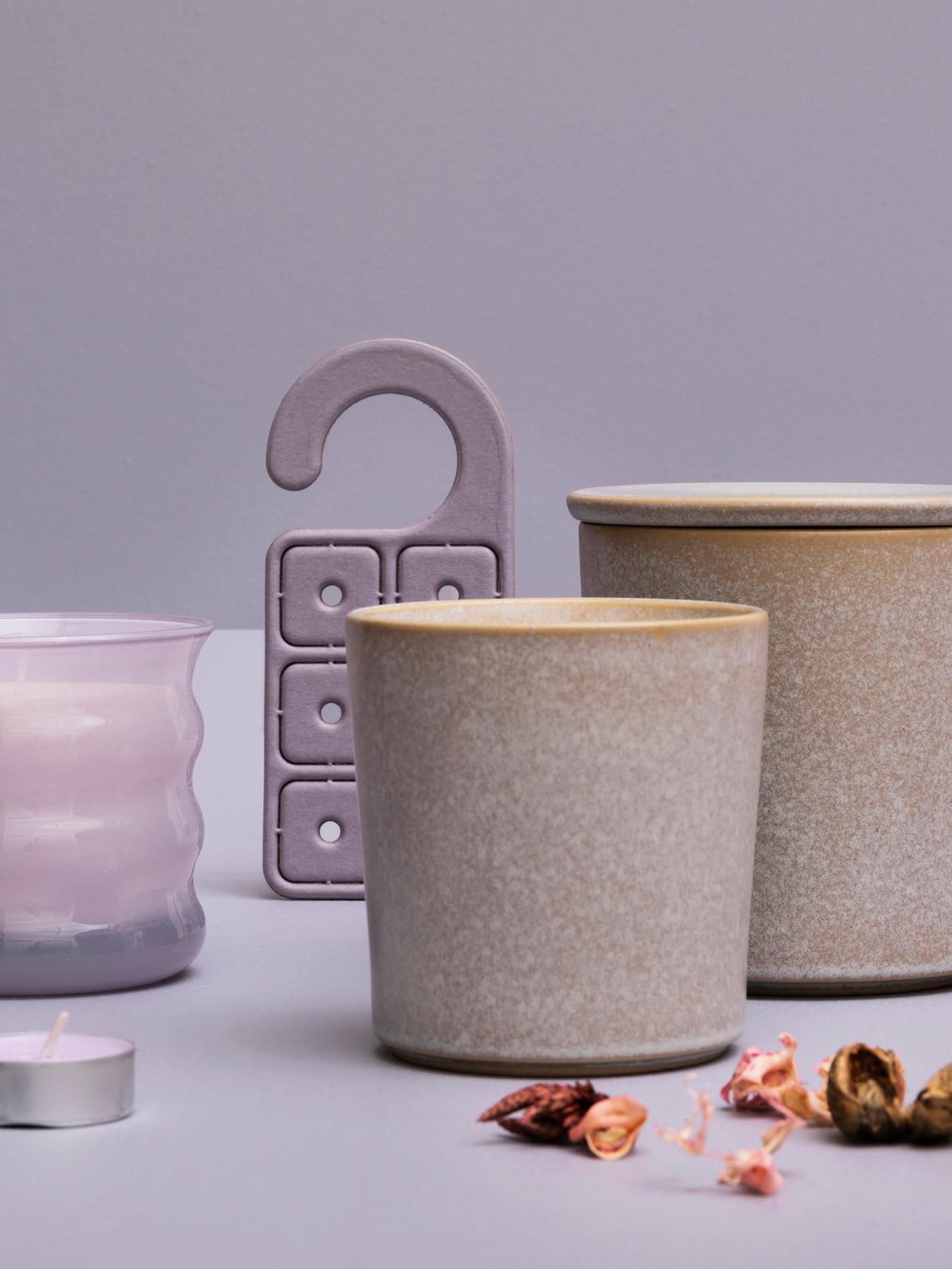 Une exposition de plusieurs bougies parfumées au pois sucré JÄMNMOD, du pot-pourri et un cintre parfumé contre un fond violet.