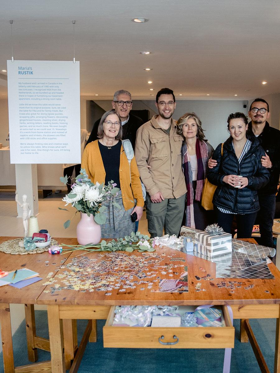 Une famille pose derrière une table IKEA RUSTIK en exposition.