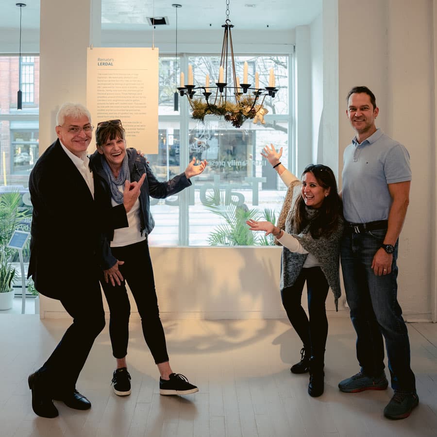 Une famille pose pour la caméra en pointant du doigt un lustre IKEA LERDAL en exposition.