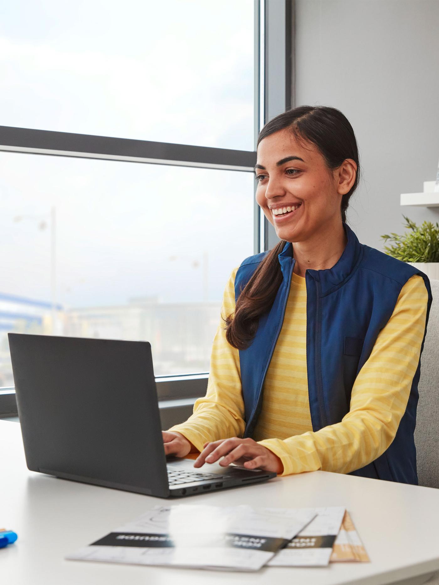 Une femme est assise à un bureau avec un ordinateur de bureau et un ordinateur portable