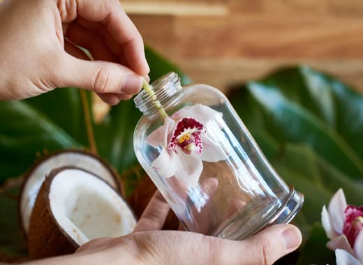 Une femme insère une orchidée dans un pot en verre.