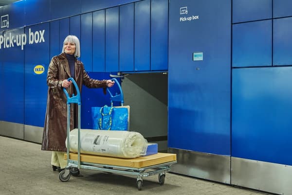 Une femme récupère sa commande IKEA dans un casier de retrait IKEA comportant des compartiments de différentes tailles.