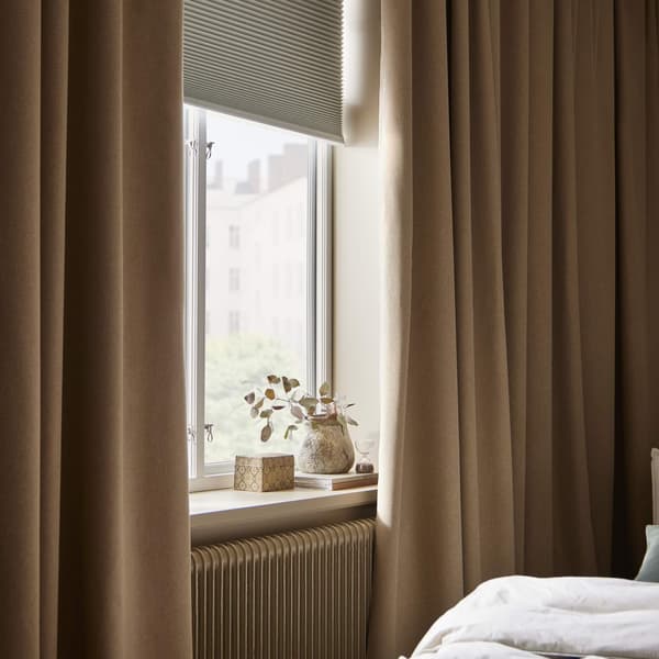 Une fenêtre de chambre avec des rideaux sombres à côté et un store occultant partiellement ouvert.