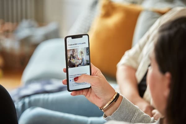 Une main tient un smartphone sur lequel s'affiche un profil IKEA Family.