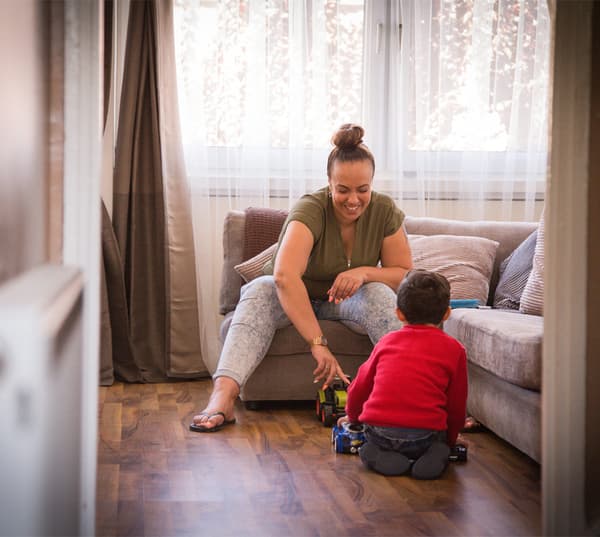 Une mère et son petit garçon dans le salon, jouant ensemble avec des petites voitures.