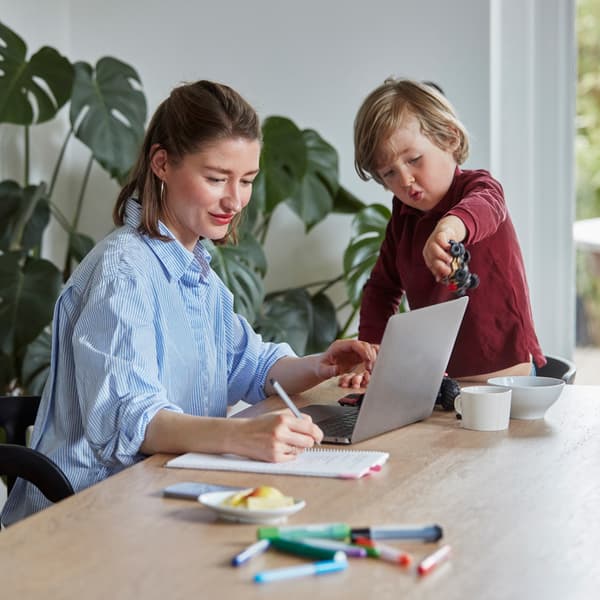 Une mère travaille à la maison ; son fils joue à ses côtés.