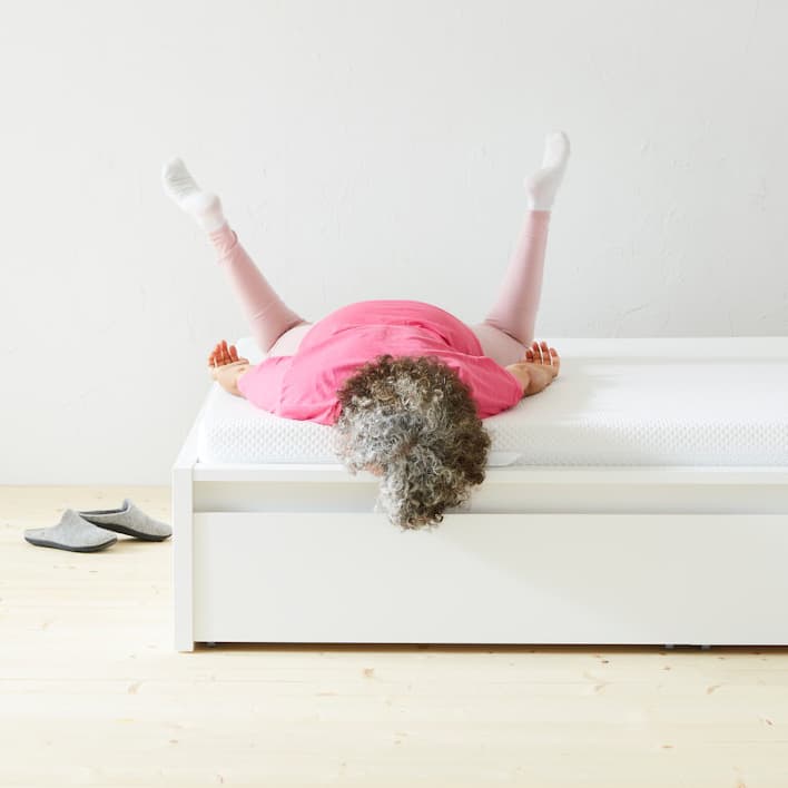 une personne allongée sur le ventre sur un matelas, les jambes en l’air