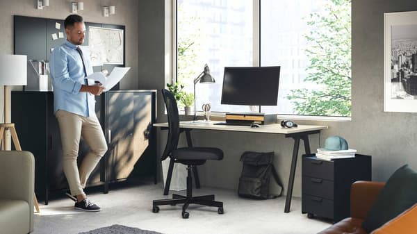 Une personne debout devant une armoire dans un bureau lit des documents.