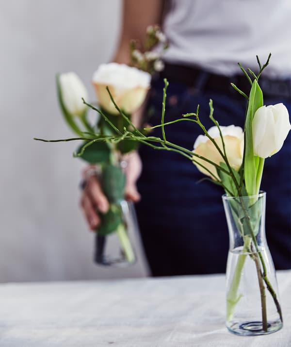 Une personne tient un vase dans sa main et un autre est posé sur une table.