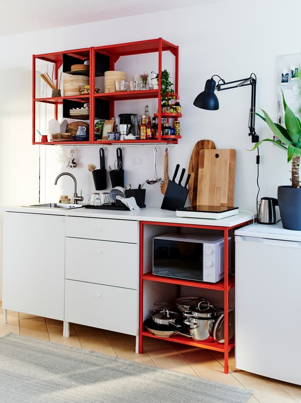 Une petite cuisine bien équipée composée d’une combinaison d’éléments ENHET– rangements ouverts en rouge, rangements fermés en blanc.