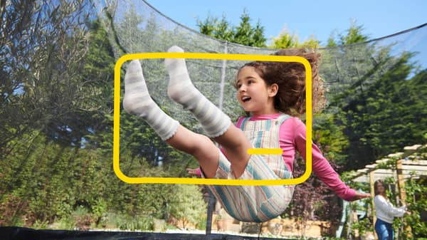 Une petite fille joue sur un trampoline dans le jardin