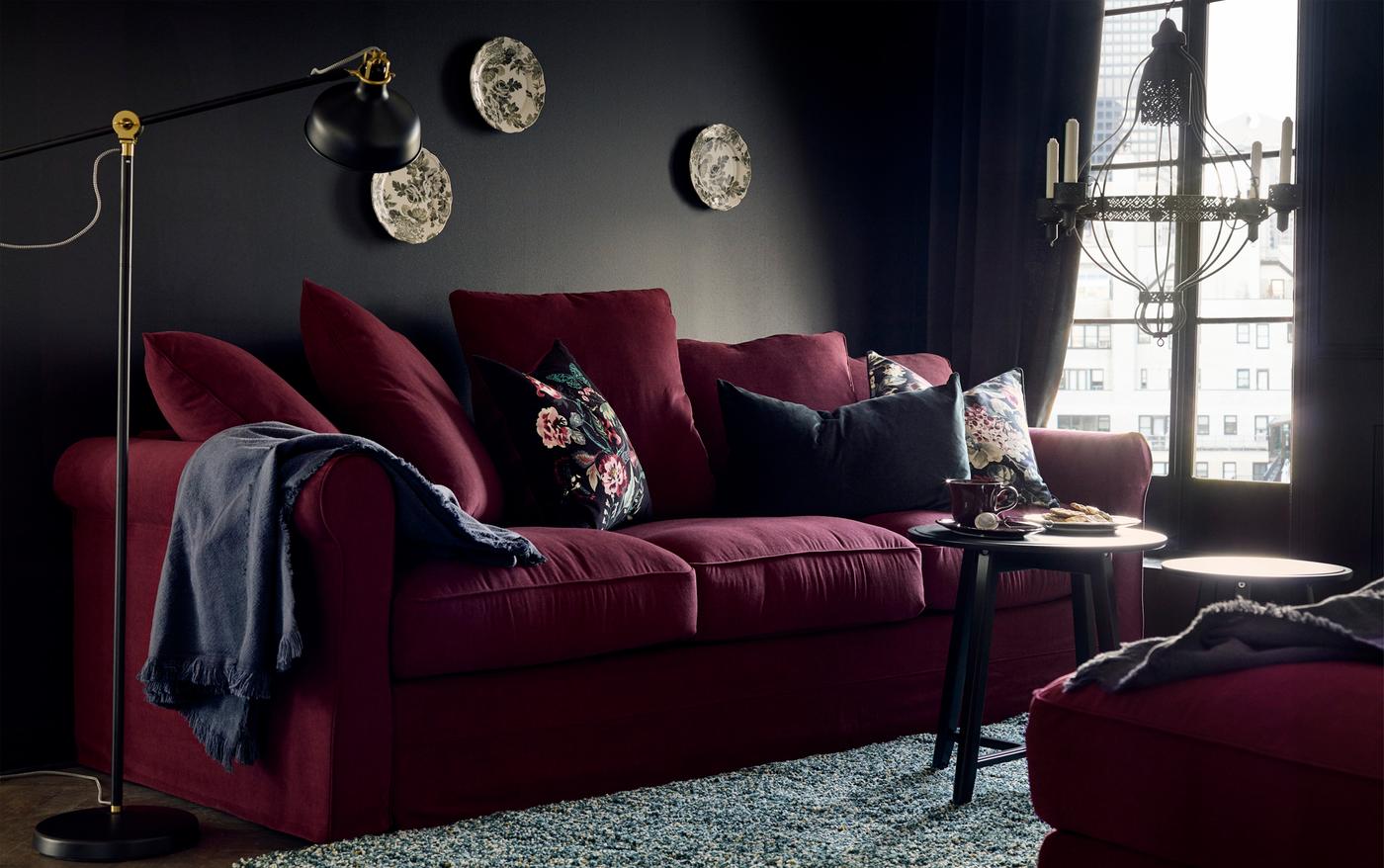 Une pièce avec un canapé garni de coussins, une lampe, des tables et des décorations murales.